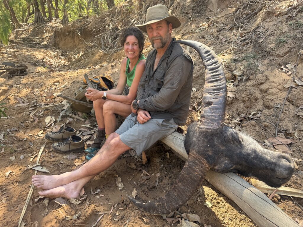 Hunters resting beside a trophy buffalo skull